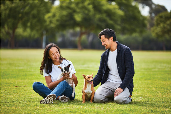 Woman and man sitting in the park with their two small dogs