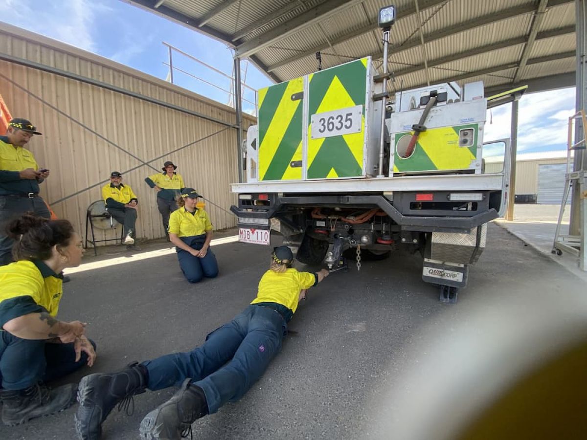 project firefighters in a maintenance area working on a truck