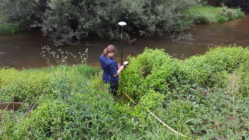 Lyndsey standing in green bush near a flowing river