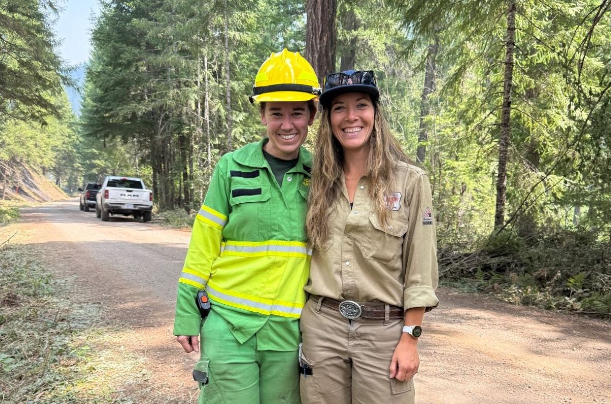 Erika on her green uniform posing with a female US firefighter