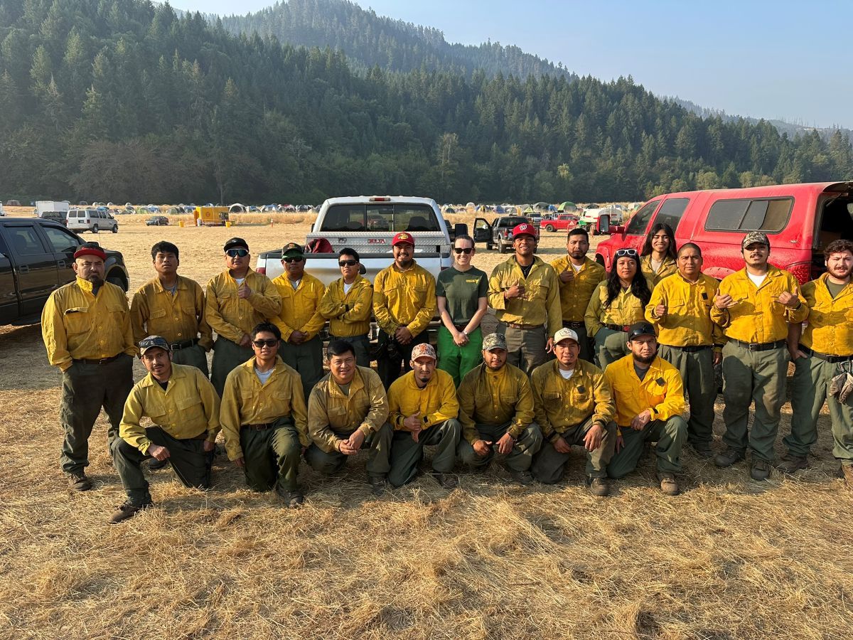 Erika in the middle of a group of firefighters wearing their yellow uniform