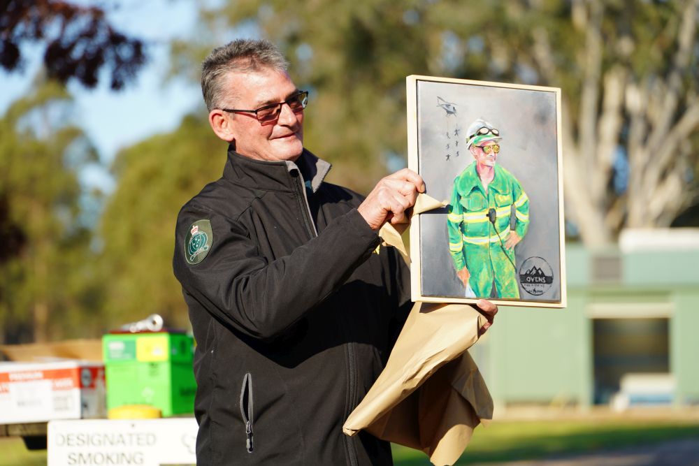 Tracy holding a painting presented at his farewell