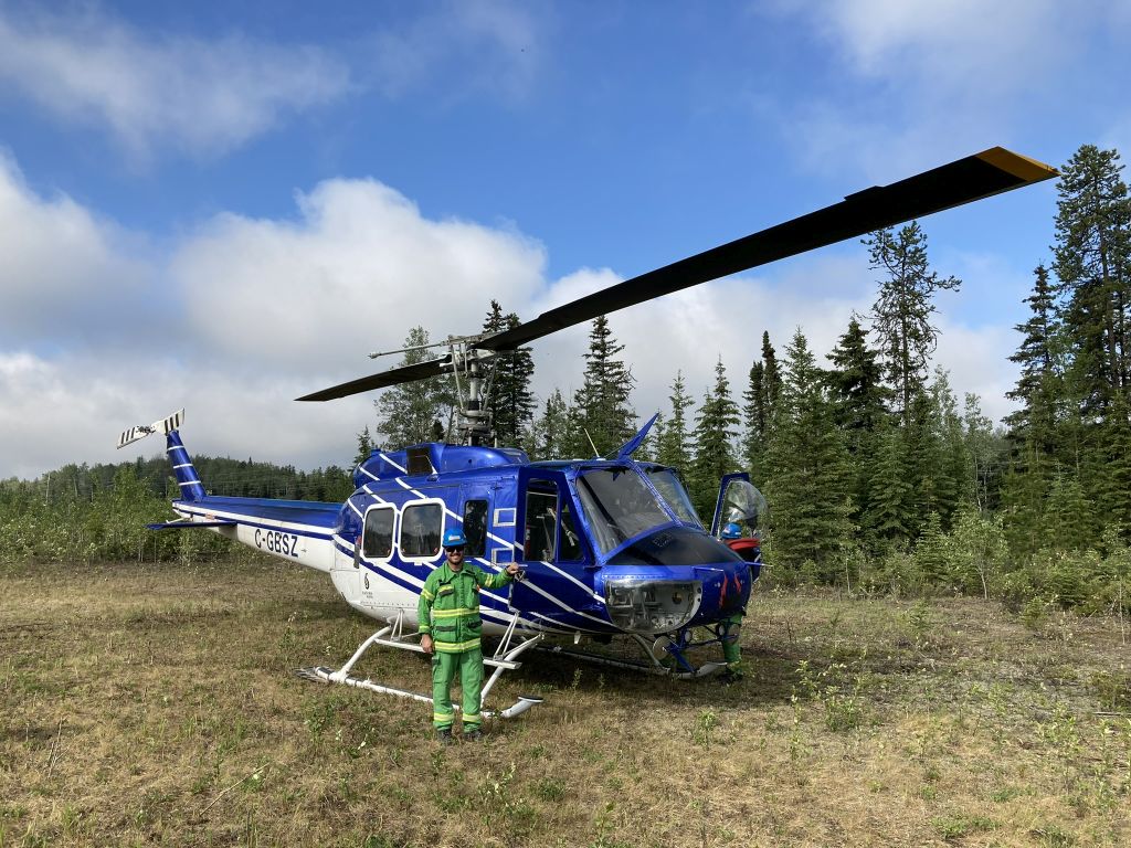 Ash next to a blue helicopter