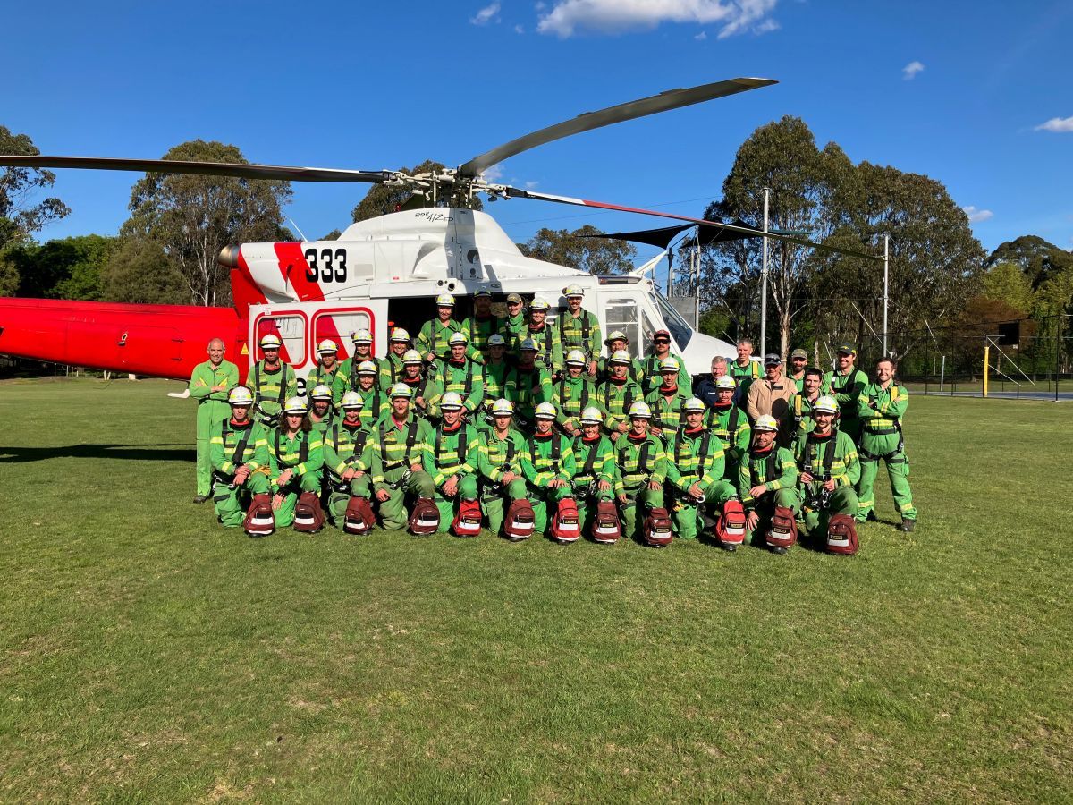 Kobei's team in a photo with a helicopter in the background