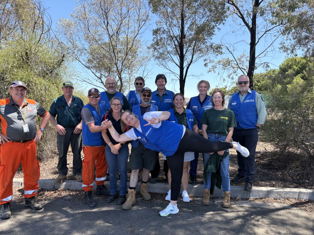 A group of people stand wearing blue vests
