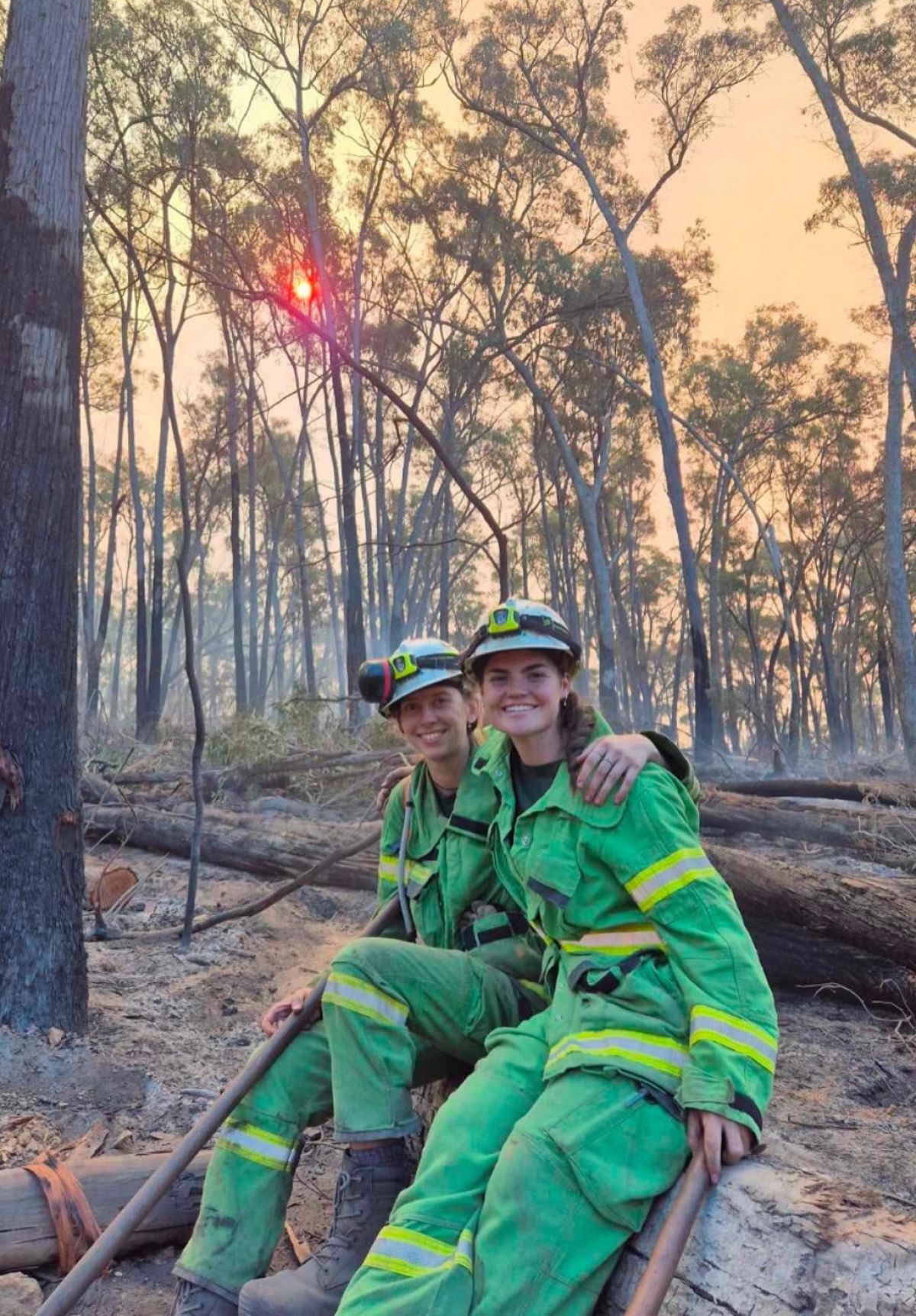 Lara with female firefighter sitting on a log