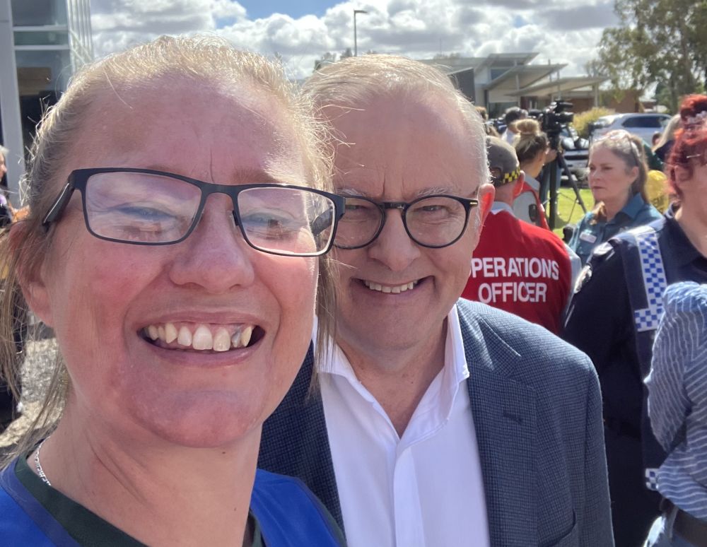 A woman is smiling and standing next to the prime minister of Australia