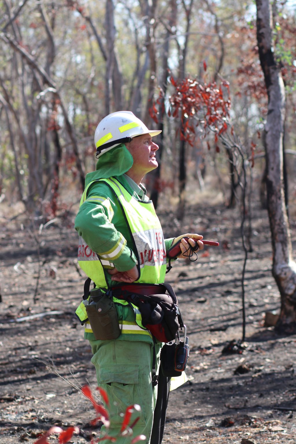 Les Vearing wearing his green overall, looking at the site. that has been burnt.