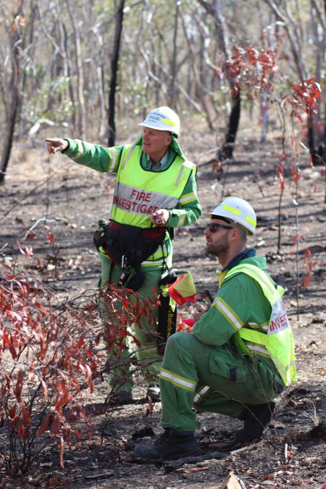 Two fire investigators in a burnt area analising the site.
