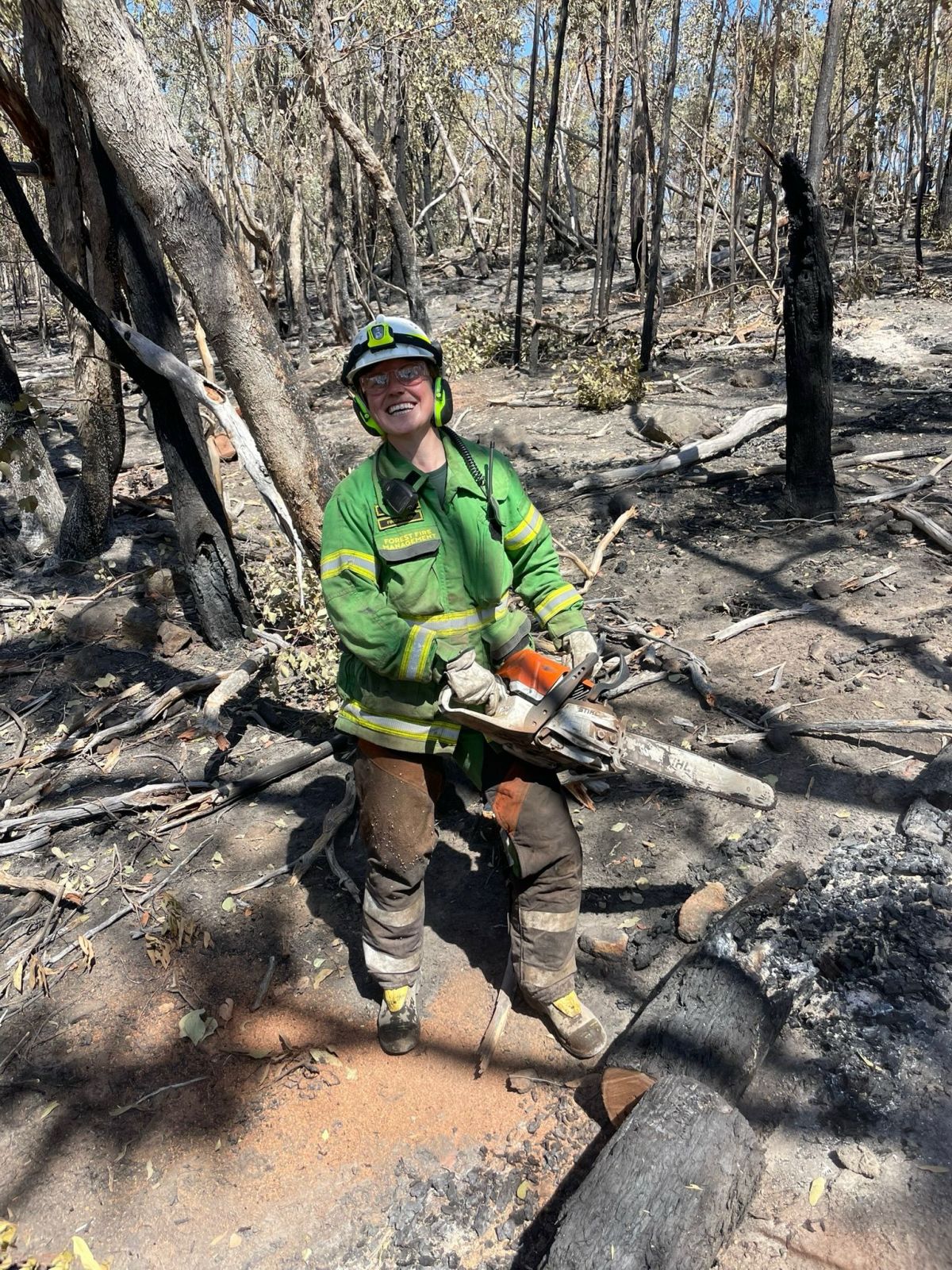 A female firefighter holds a chainsaw on the fireground