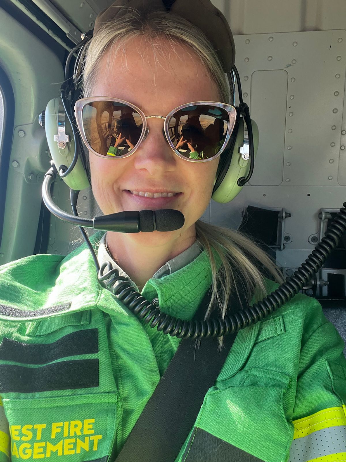 Close up of Lauren Todman in sunglasses and with a headset on in a helicopter
