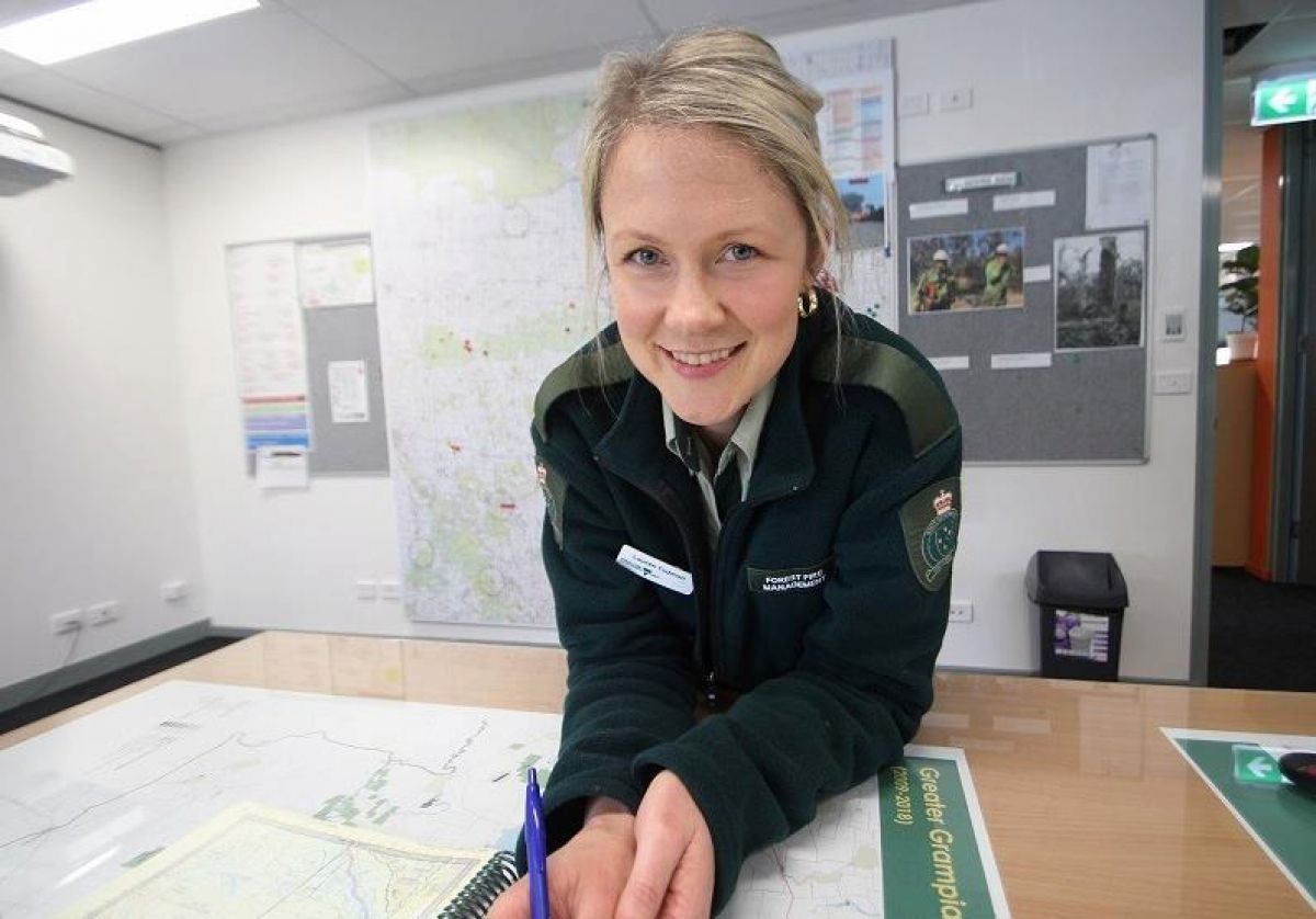 Lauren Todman in dark green jumper leans over a map