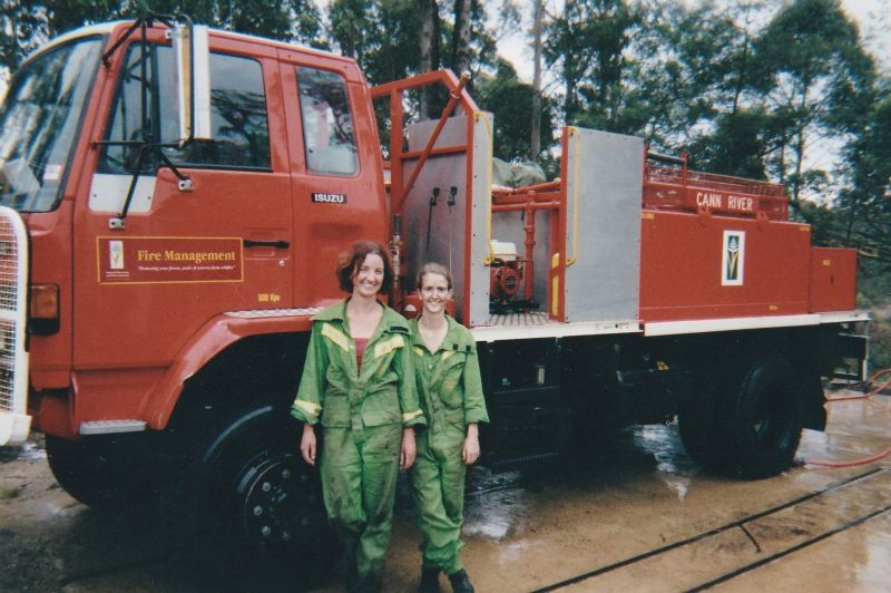 Two women standing in front of a red fire management truck