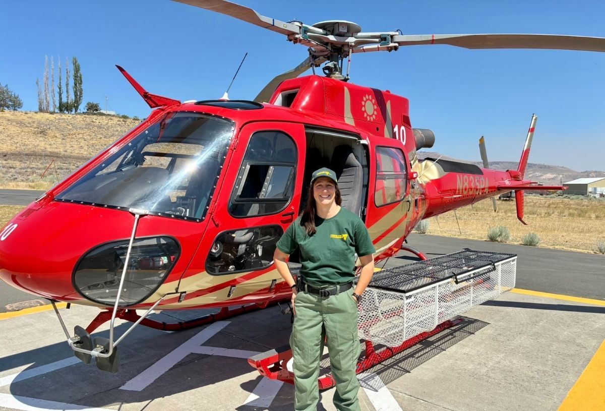 Beth posing in front of a red helicopter
