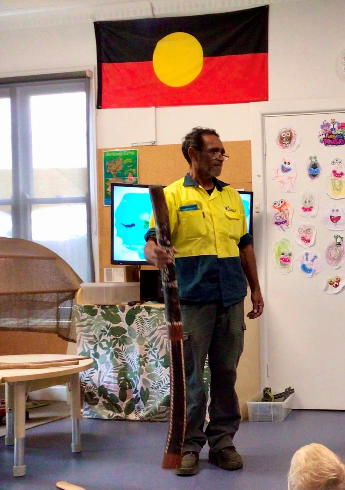 Uncle Will holding a didgeridoo in his hand while talking to students